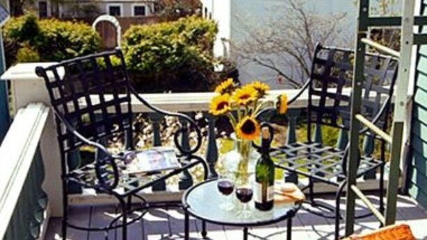 Una terraza con mobiliario exterior, una mesa con una botella y vasos, y girasoles.