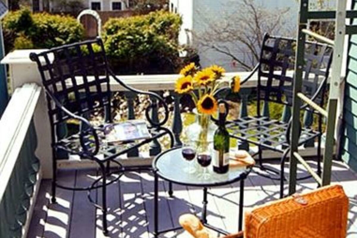 A deck with outdoor furniture, a table with a bottle and glasses, and sunflowers.