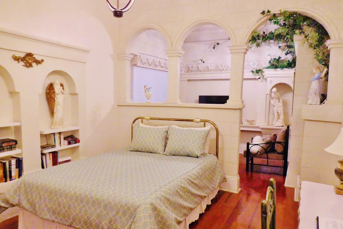 A bedroom with a bed, bookshelves, a desk, and a chair.