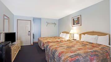 A hotel room with two beds, a TV, a dresser, and a door.