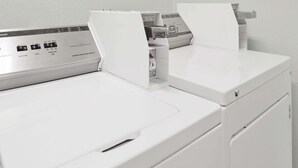 Vue de face d’une buanderie moderne et blanche, avec un panneau de commande et un sèche-linge.