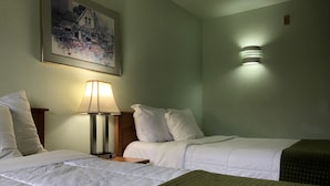 Une chambre d’hôtel avec deux lits, une table de chevet avec une lampe, un tableau au mur et un luminaire fixé au mur.