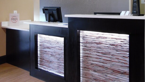A reception desk with a clock, a Baymont Inn sign, and a black counter.