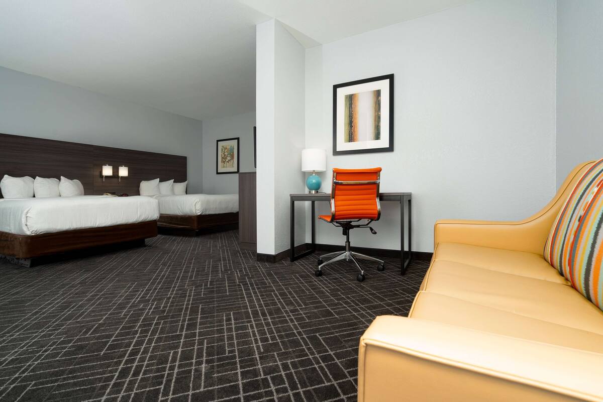 Een hotelkamer met twee bedden, een bureau, een stoel en een bank.