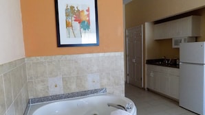A bathroom with a bathtub, a sink, and a framed artwork on the wall.