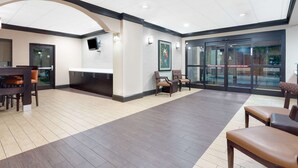 A hotel lobby with a reception desk, seating area, and a glass entrance.