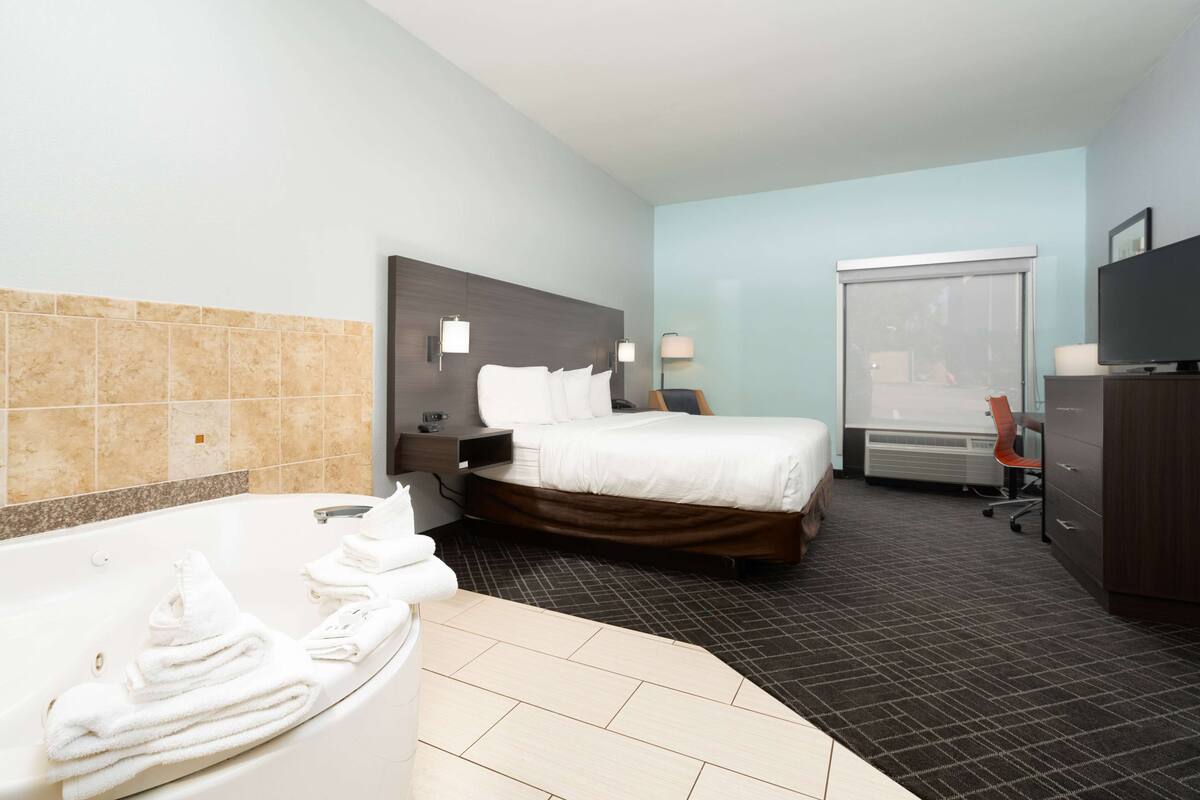 Hotelkamer met een groot bed, een aparte badkamer met bad, een bureau, een stoel en een televisie.