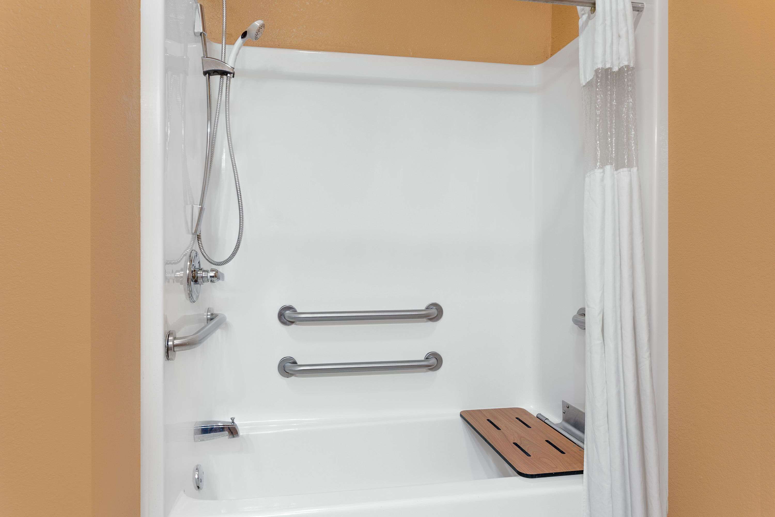 Ducha con cabezal de ducha de mano, dos barras de apoyo y un recipiente de madera.