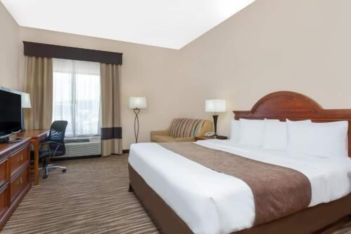 Een hotelkamer met een bed, een bureau met een televisie, een stoel en twee lampen.