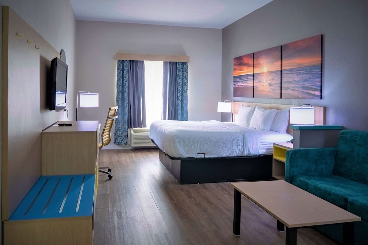 Ein Hotelzimmer mit Bett, Schreibtisch, Stuhl und einem Bild an der Wand.