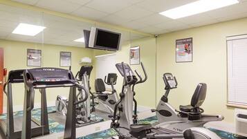 Un gimnasio con cintas de correr, elípticas y una bicicleta estática.