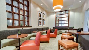 A modern restaurant with high ceilings, large windows, and a mix of seating options including booths and tables.