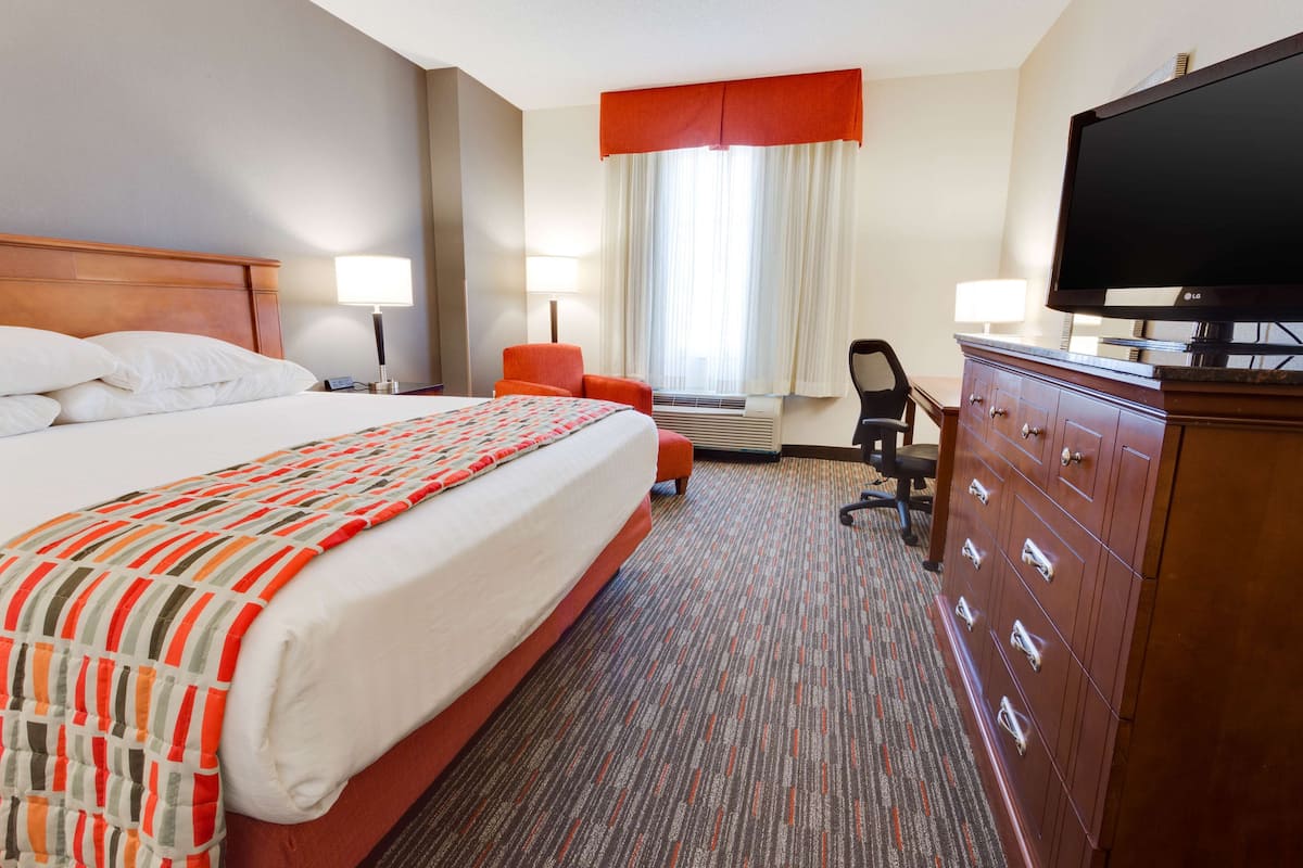 Une chambre d’hôtel avec un grand lit, un bureau, une télévision et une commode.