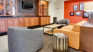 A modern hotel lobby with a wooden cabinet, a flat-screen TV, a sofa, and a table.