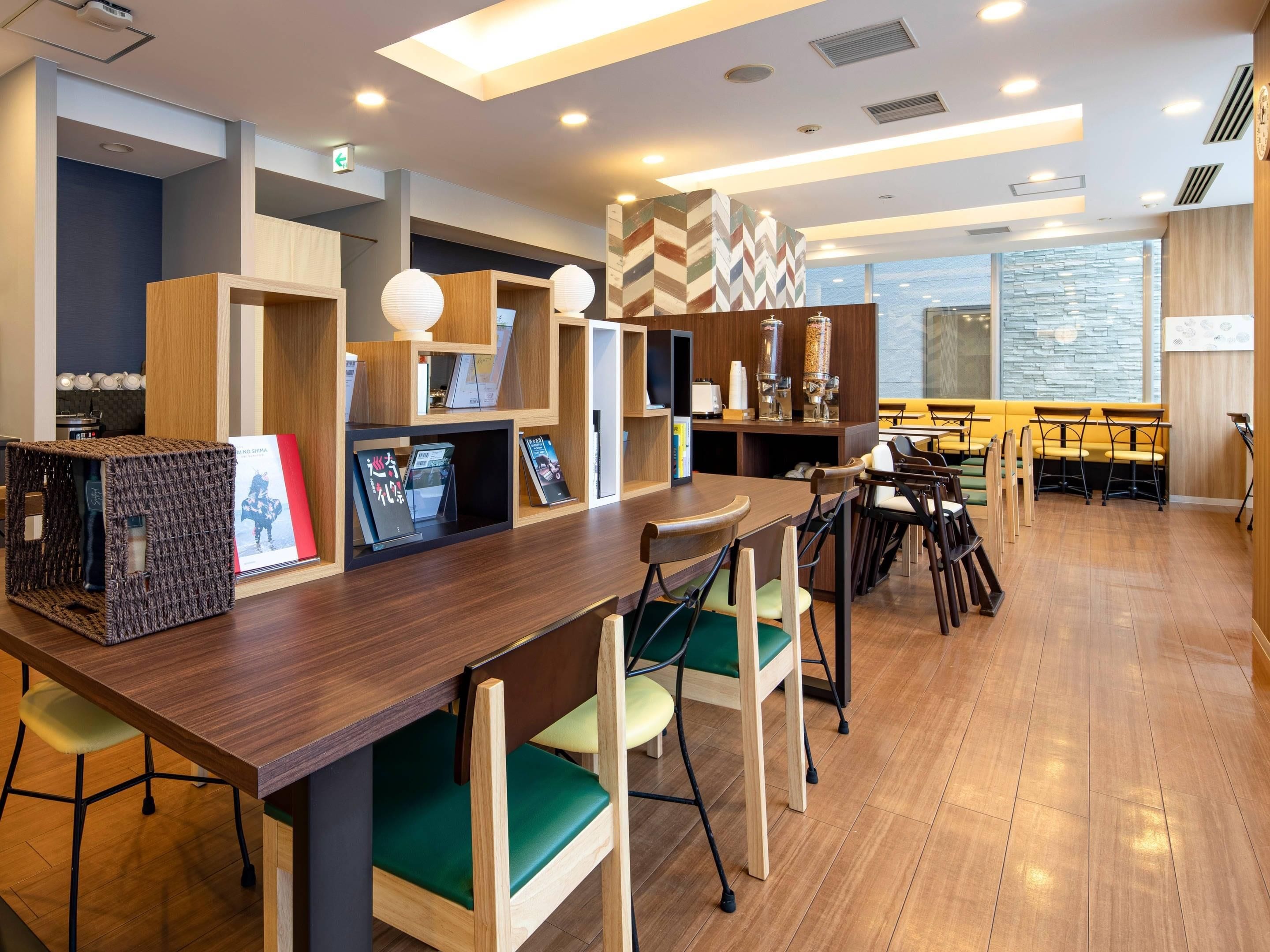 Un café moderne, doté de mobilier en bois, d’un long comptoir et offrant une vue sur la ville grâce à de grandes fenêtres.
