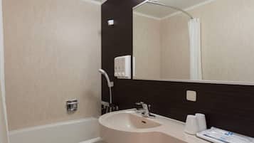 Ein Badezimmer mit Badewanne, Waschbecken, Spiegel und Handtuchhalter.