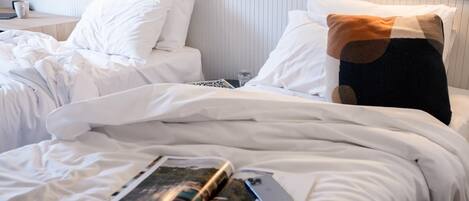A hotel room with a neatly made bed, a bedside table with a lamp, and a wall-mounted shelf.