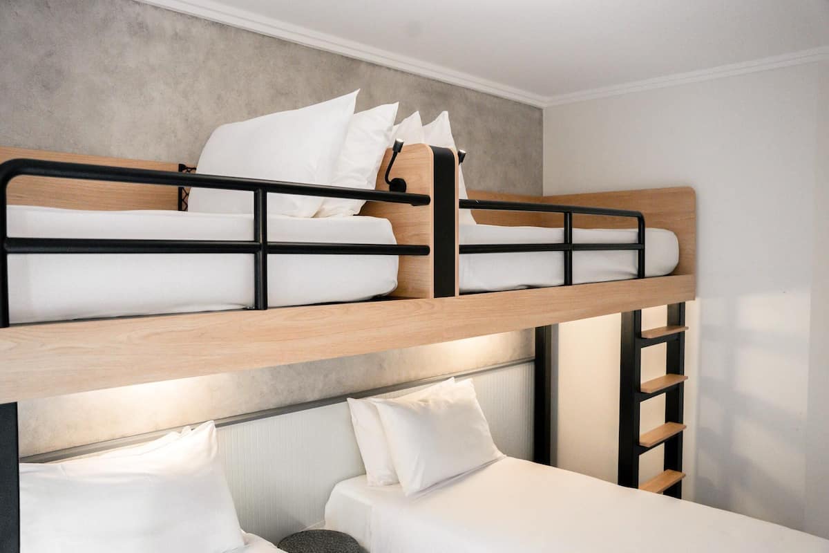 Ein Stockbett mit weißer Bettwäsche und einem Holz-Kopfteil.