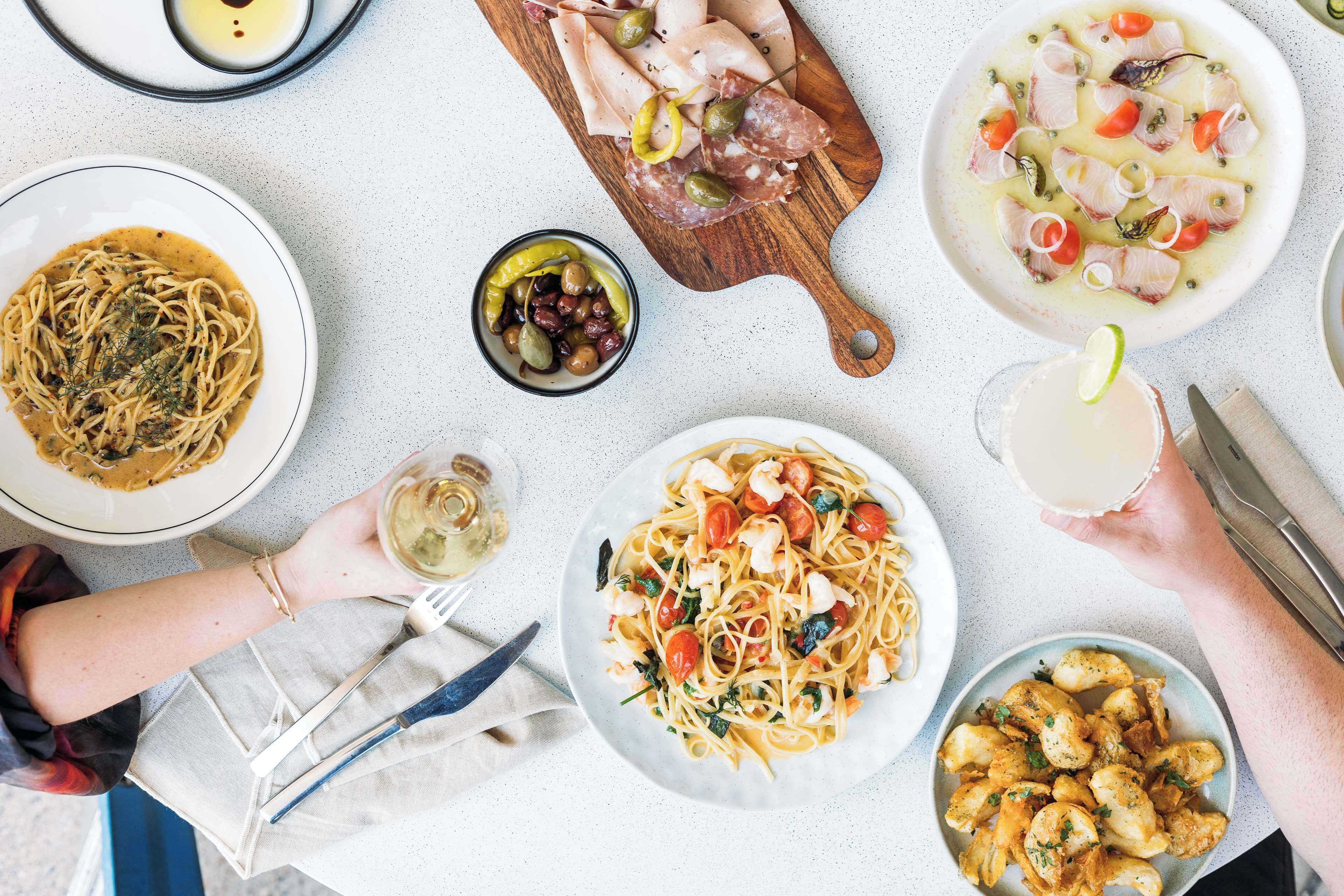 Una mesa con diferentes platos, como pasta, mariscos y una bebida.