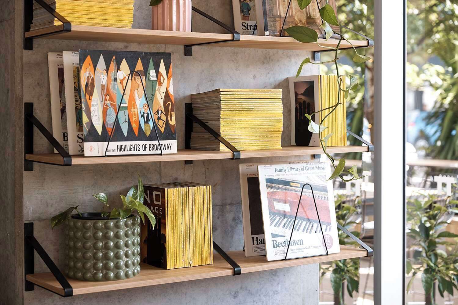 Ein Bücherregal mit verschiedenen Büchern und Dekorationsobjekten, darunter ein gerahmtes Bild und ein Topf mit Pflanze.