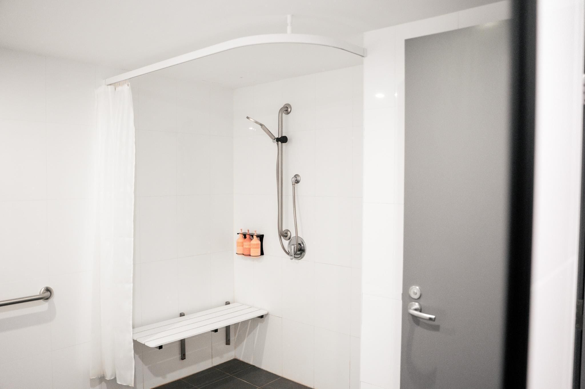 Un bagno moderno e piccolo con doccia, una panca bianca e una porta.
