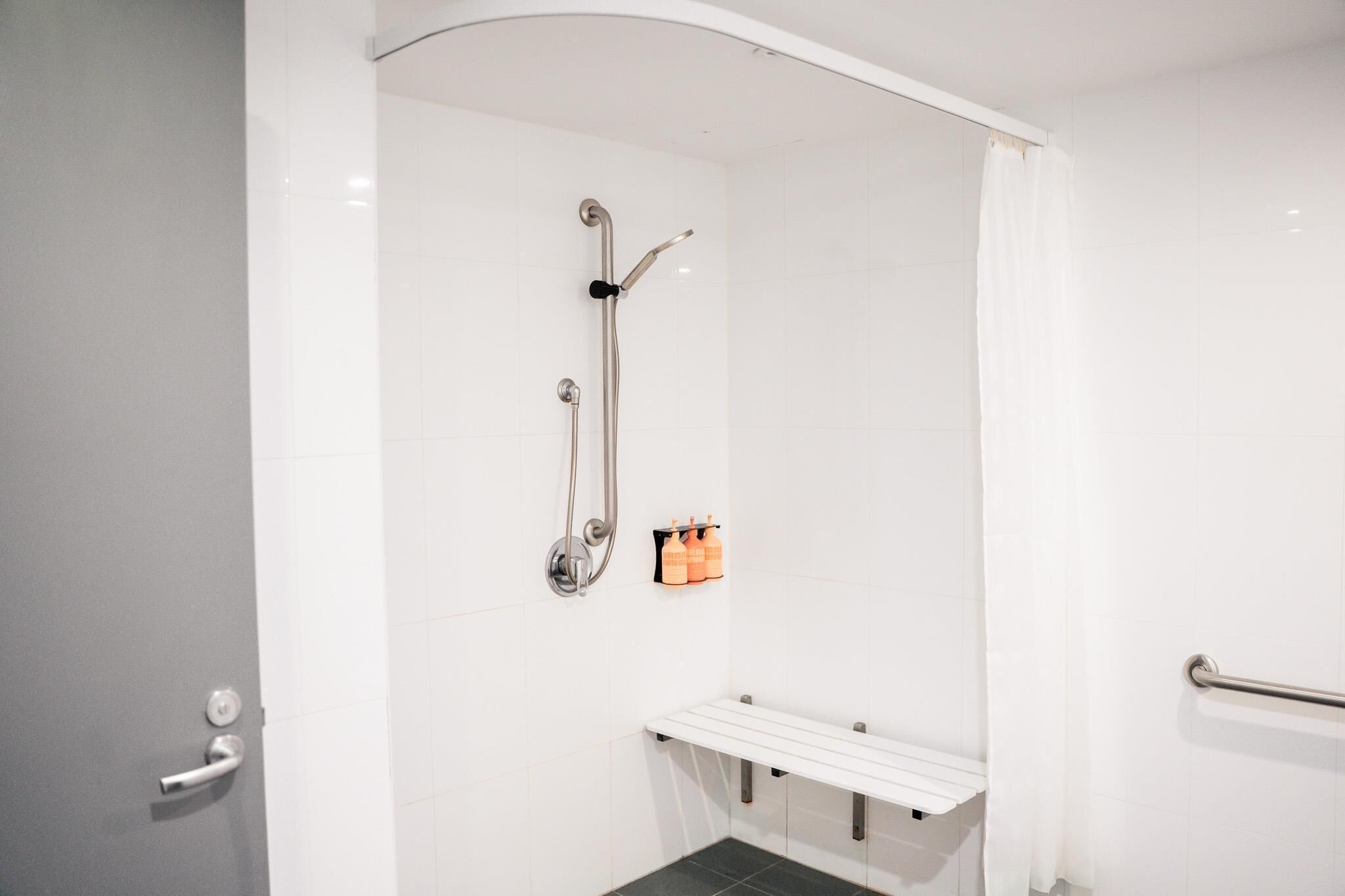 A modern bathroom with a shower, a toilet, and a bench.