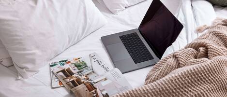 Ein Laptop auf einem Bett mit einer Zeitschrift und einer kleinen Holzschatulle.