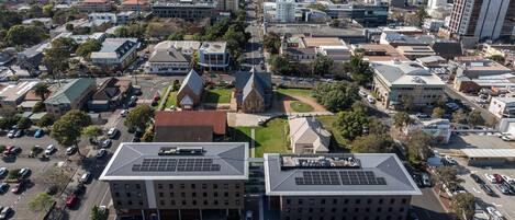 Vista aerea di un paesaggio urbano con edifici residenziali e commerciali, una chiesa in evidenza e un’ampia area di parcheggio.