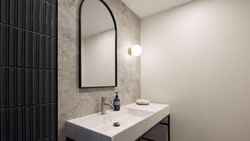 A modern bathroom with a rectangular sink, a large mirror, and a wall-mounted light fixture.