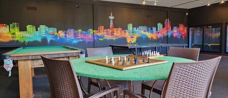 A pool table with a green felt surface, surrounded by wicker chairs.