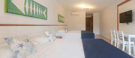 A hotel room with a large bed, a smaller bed, a desk, and a television.