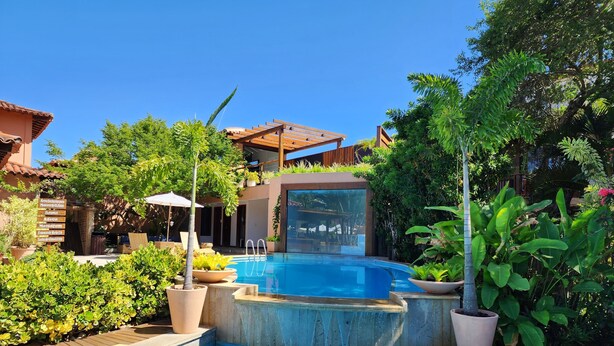 A swimming pool with a hot tub, surrounded by lush greenery and a wooden deck. - Pousada Corais e Conchas (Búzios)