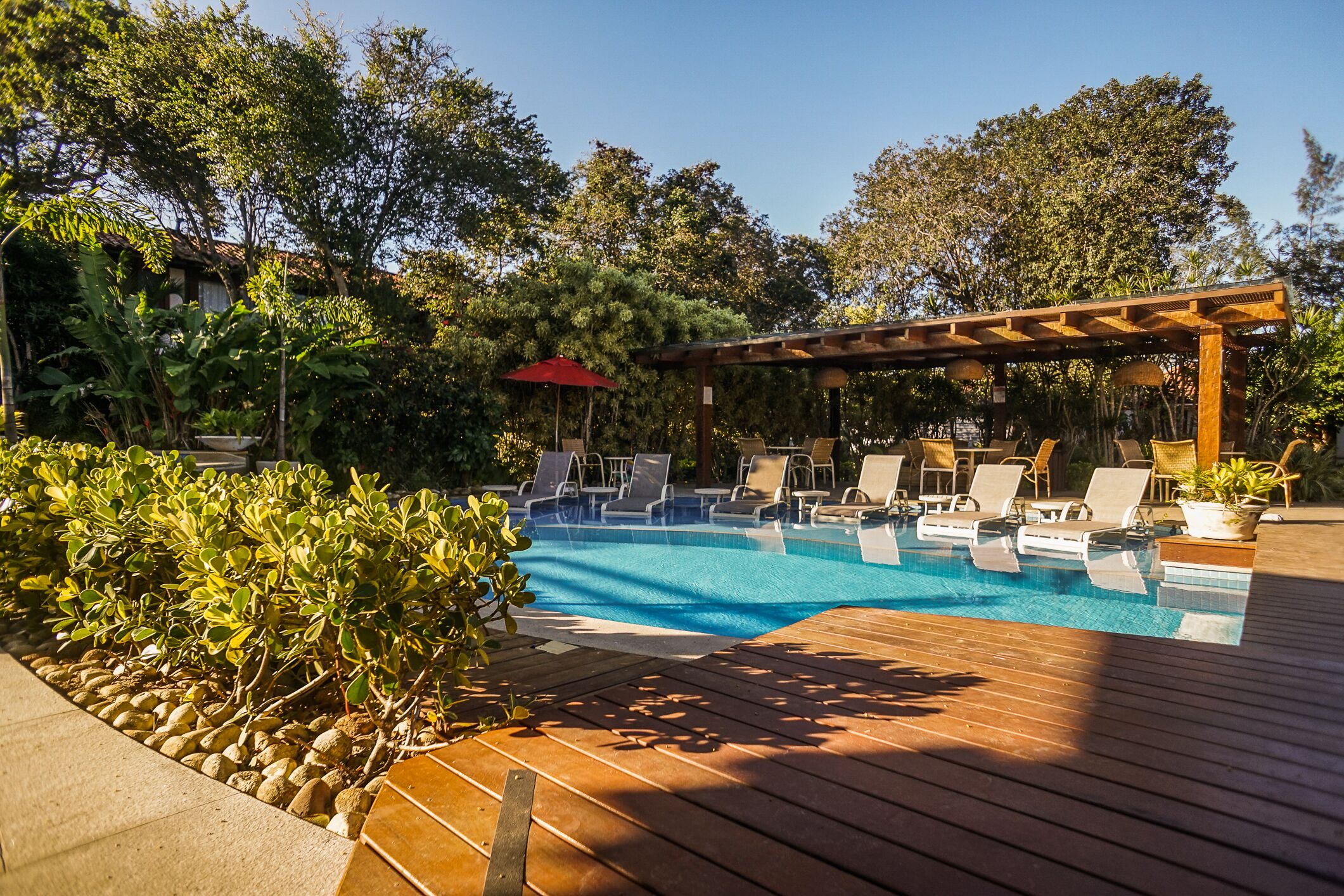 A pool area with lounge chairs and a pergola.