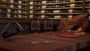 A wine rack with bottles, two wine glasses on a counter, and a wine opener. - Pousada Corais e Conchas (Búzios)