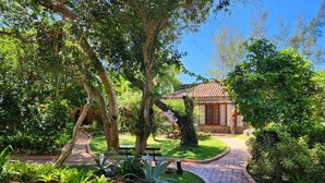 A garden pathway leading to a building with a tiled roof and a stone facade. - Pousada Corais e Conchas (Búzios)