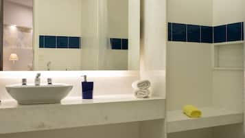 A bathroom with a white sink, blue tiles, a mirror, and a towel rack.