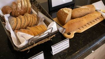 Una exhibición de panes integrales, incluyendo baguettes y bollos, sobre un mostrador con etiquetas.