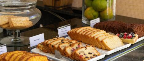 A display of various baked goods including cakes and biscuits, with labels indicating flavors like "Budin Ingles" and "Torta di Vaniglia".