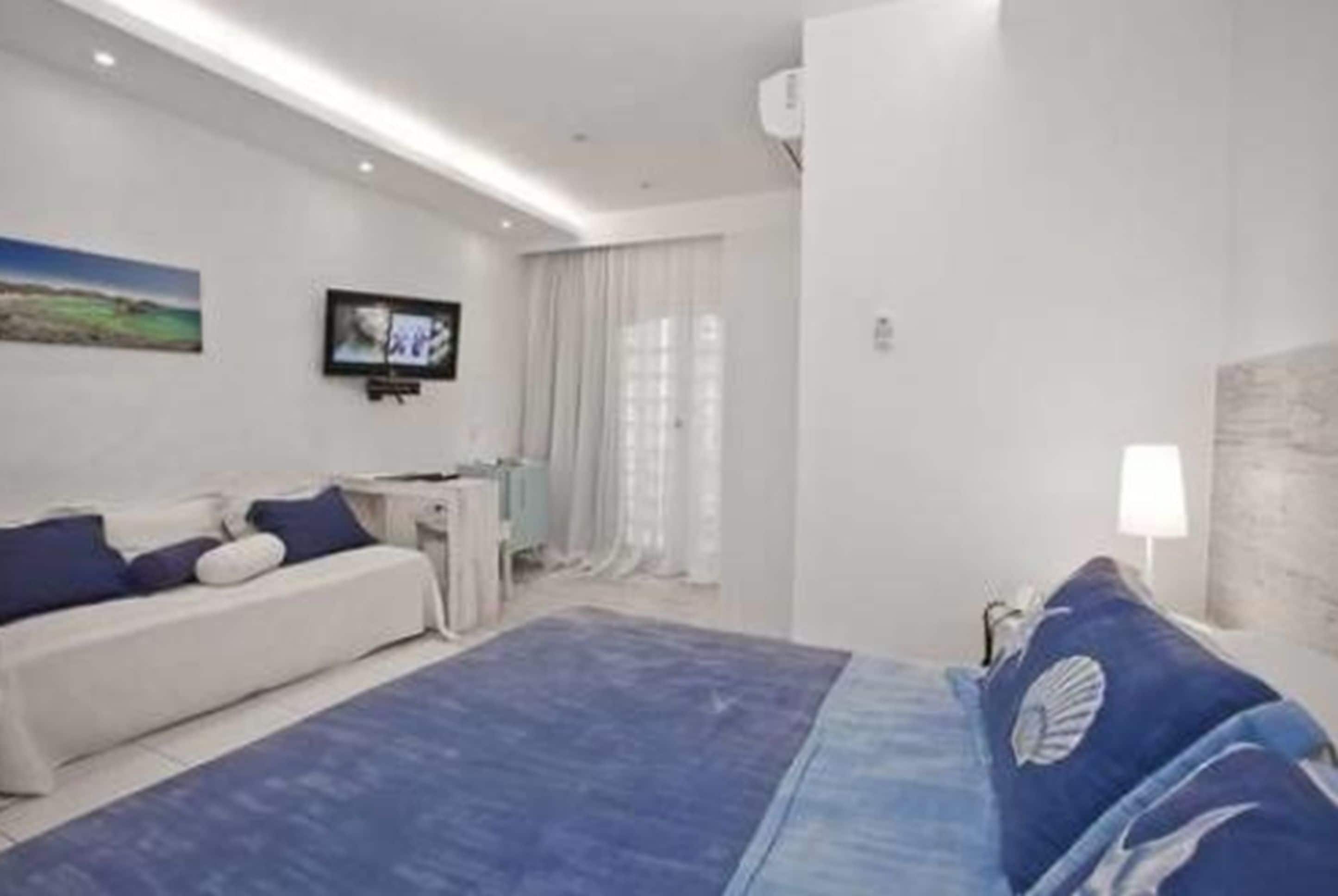 Una habitación de hotel moderna con una cama, un sofá, un televisor y un cuadro en la pared.
