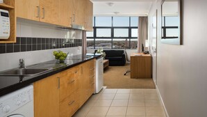 Une cuisine moderne avec des meubles en bois, un plan de travail noir et une vue sur la ville grâce à de grandes fenêtres.