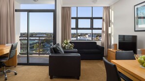 Une chambre d’hôtel avec une grande fenêtre, un canapé, une table à manger et un téléviseur.