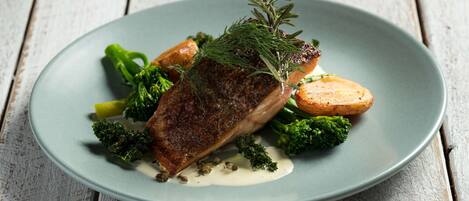 A plate with a piece of meat, broccoli, and potatoes on a rustic wooden table.