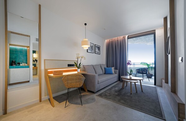 Una sala moderna con sofá, mesa de comedor, silla de mimbre y balcón con vistas.