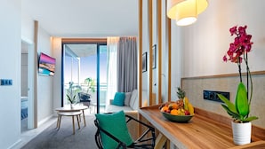Una habitación de hotel moderna con comedor, vistas al exterior y un frutero en la mesa.