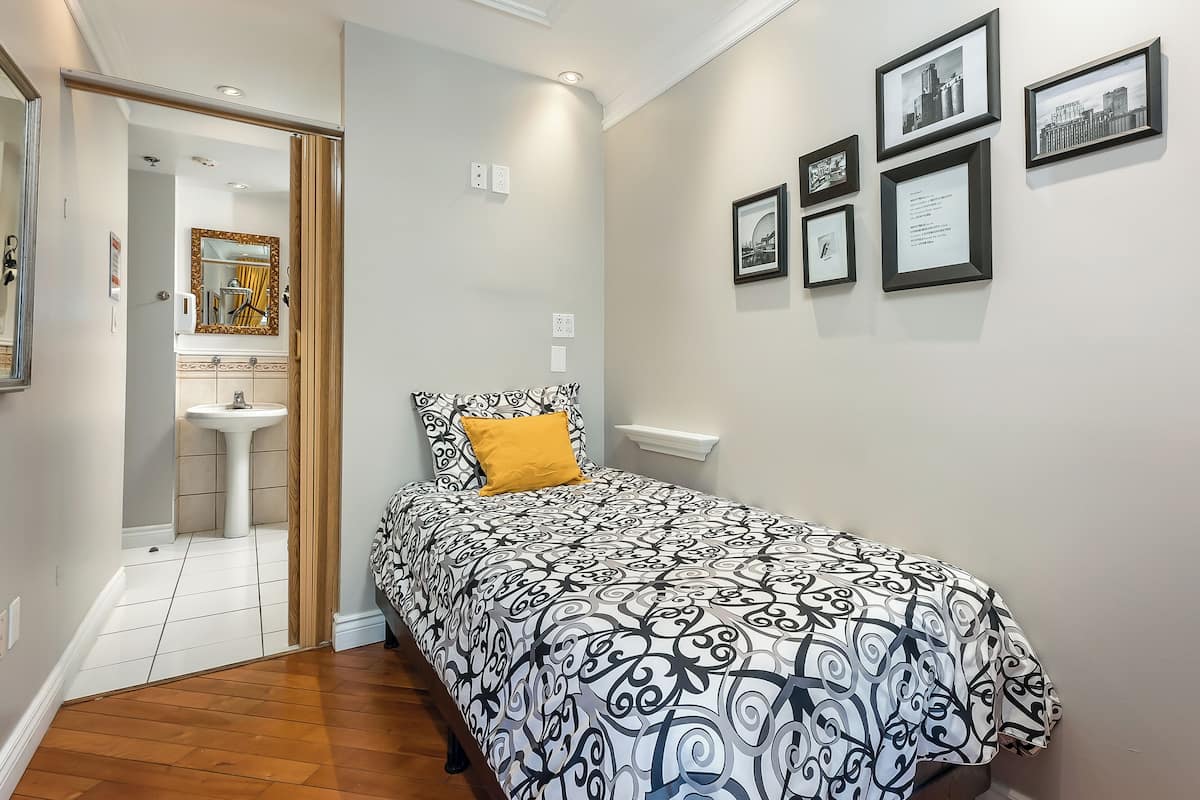 Quarto com cama, mesa de cabeceira, espelho e parede decorada com quadros.