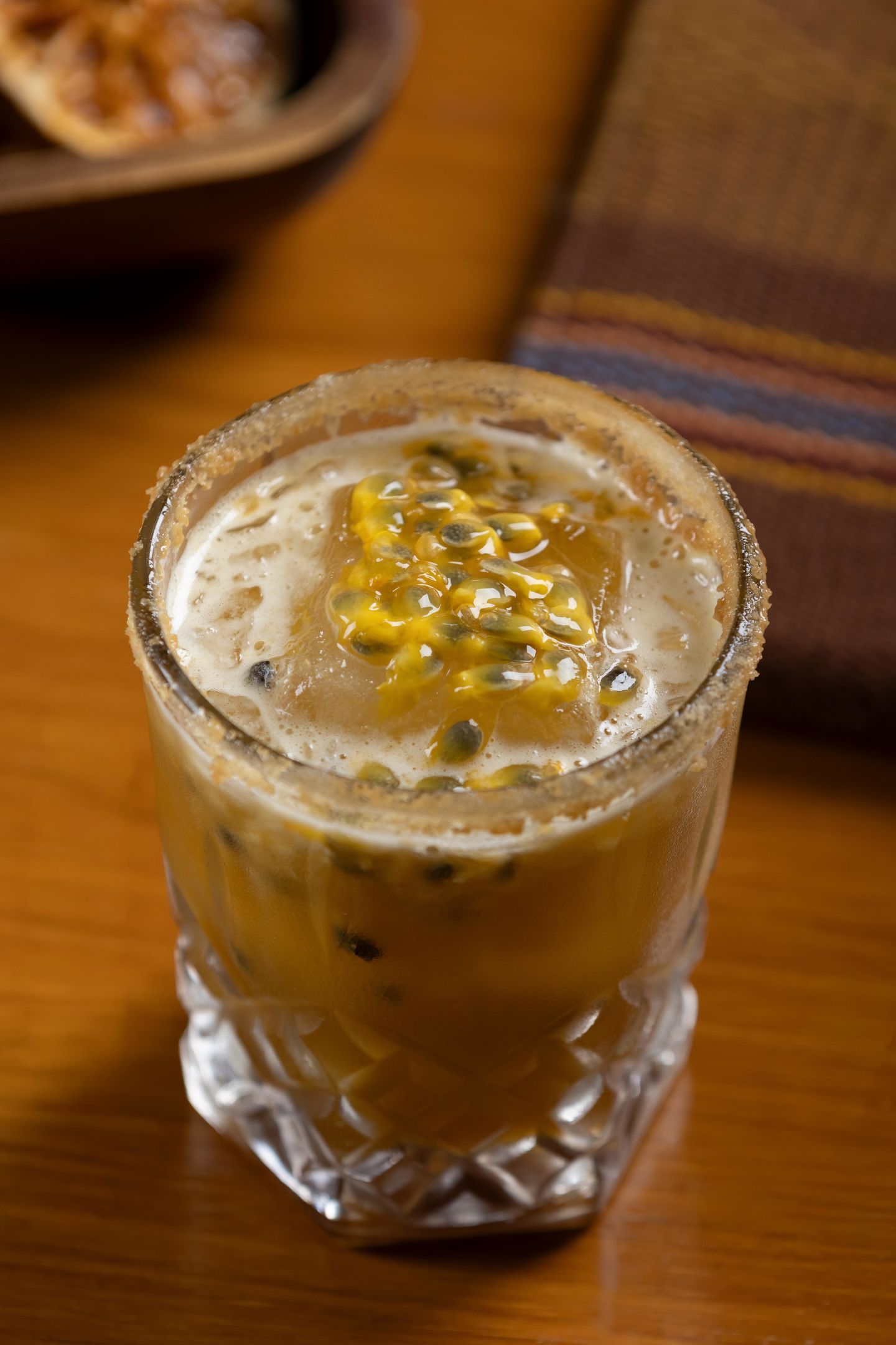 Un verre contenant une boisson mousseuse et des graines, peut-être des graines de fruit de la passion, posé sur une table en bois.
