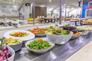 Un bufé con ensaladas y frutas variadas.