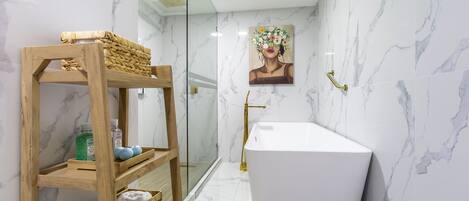 A modern bathroom with a freestanding bathtub, a wooden shelf with baskets, and a glass shower enclosure.