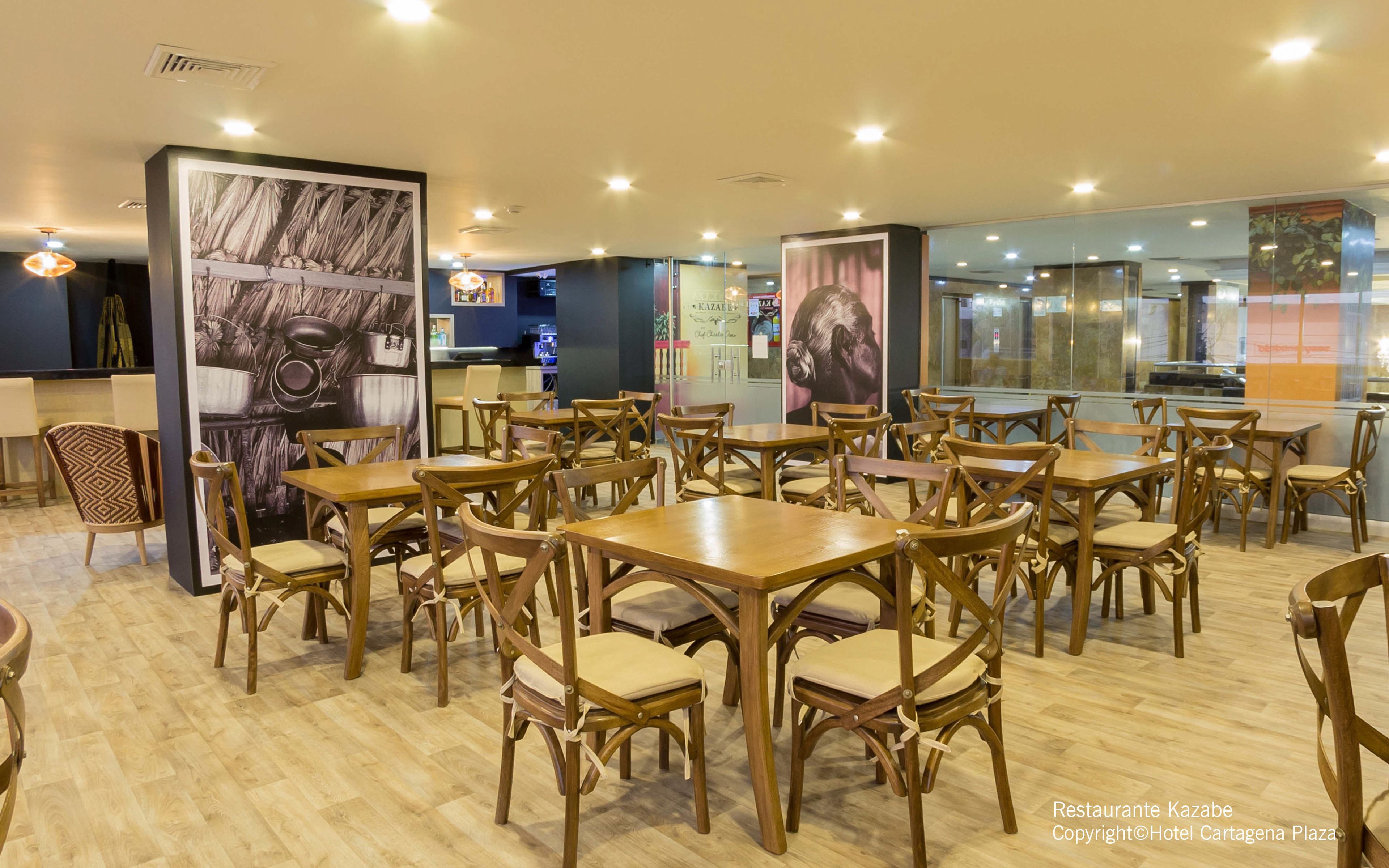Un restaurant avec des tables et des chaises en bois, un espace cuisine et une vue sur la rue grâce à un mur en verre.