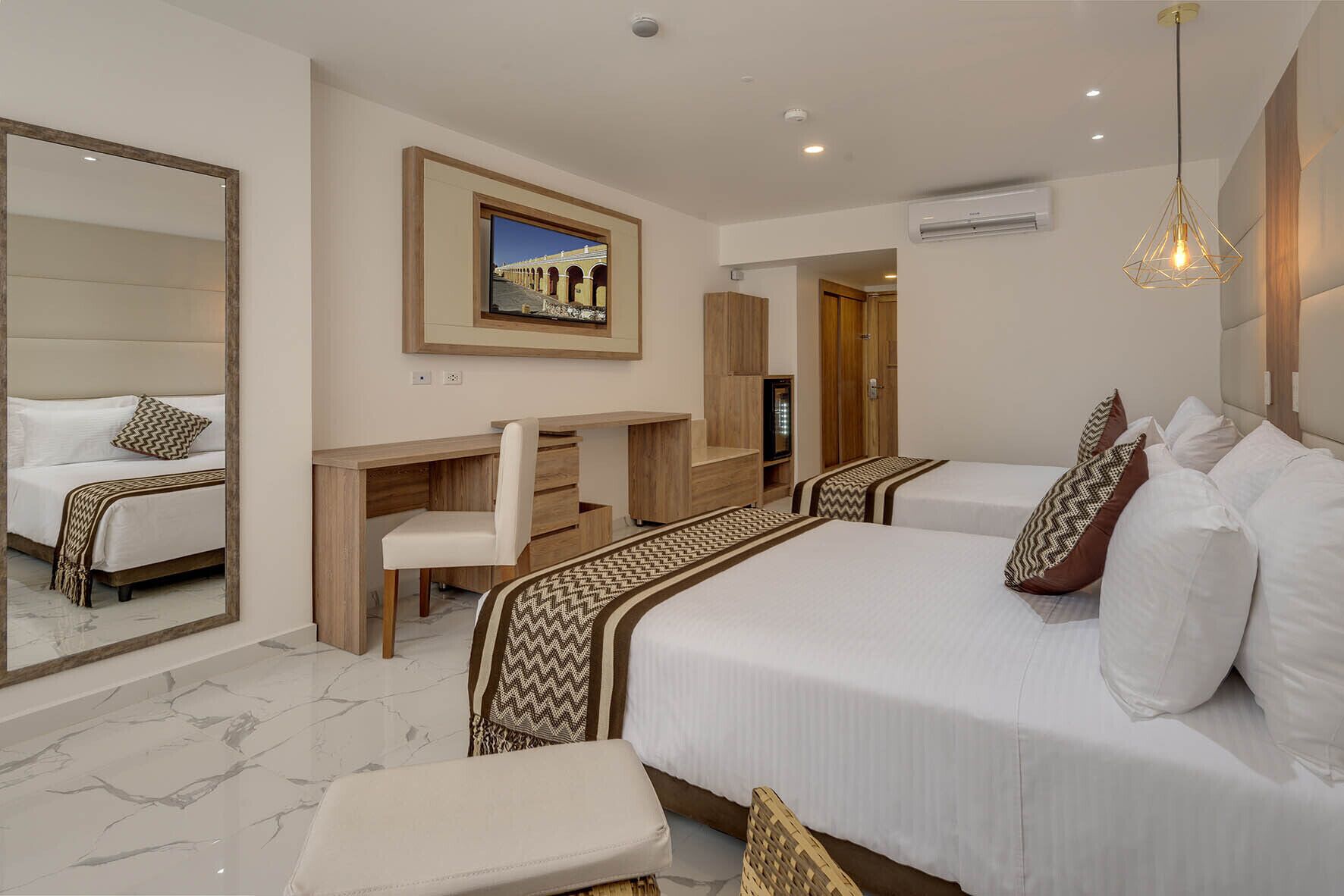 Una habitación de hotel con una cama grande, un escritorio, una silla, un espejo y un televisor.